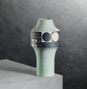 An aqua coloured vase with a wider section in the upper half featuring retro geometric patterns in charcoal and white Homage to Forton, 2023, white stoneware by Jo Walker, presented by Craft Scotland. Photo Shannon Tofts